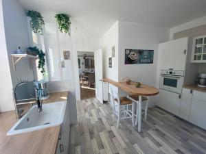 een keuken met een wastafel en een tafel. bij Le cottage des Vaux avec cheminée, sauna et jacuzzi dans un parc arboré in Senlisse