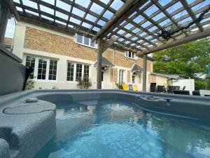 a swimming pool with a pergola in a backyard at Le cottage des Vaux in Senlisse
