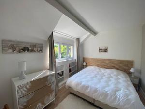 een witte slaapkamer met een bed en een raam bij Le cottage des Vaux avec cheminée, sauna et jacuzzi dans un parc arboré in Senlisse +23 foto's