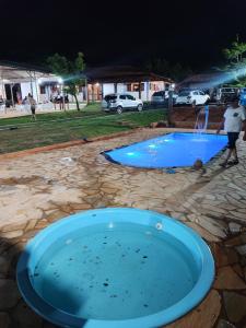 una piscina di notte con un uomo accanto di Sitio Cheiro Do Campo a Jaboticatubas