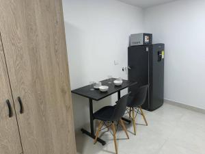 uma mesa com cadeiras e um frigorífico num quarto em Apartaestudio 203 Gaitán em Bogotá