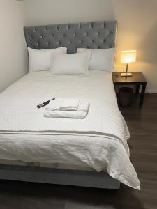 ein großes weißes Bett mit einem silbernen Kopfteil und einer Lampe in der Unterkunft Comfortable 3 Bed Basement Unit in Winnipeg