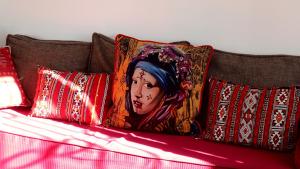 uma cama com almofadas com um quadro de uma mulher em Dar Baida Bouznika Plage David em Bouznika