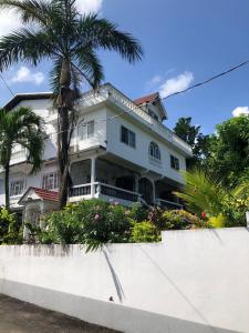 una casa blanca con una palmera delante de ella en Happy Grove Lodge, 