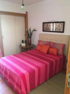 ein Schlafzimmer mit einem großen rosa Bett mit orangefarbenen Kissen in der Unterkunft Soltroia Beach House in Carvalhal