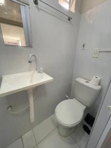 a white bathroom with a toilet and a sink at Quitinete da Nicole in Canindé de São Francisco
