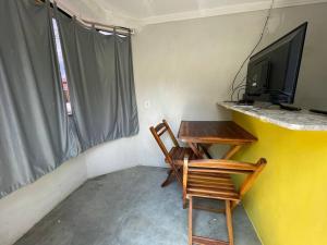 een kamer met een tafel, een tv en een stoel bij Quitinete da Nicole in Canindé de São Francisco