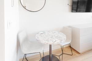 - une table ronde avec 2 chaises blanches et un miroir dans l'établissement Mellow on Meadow Mile 2B, à Fraser