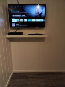 una TV a schermo piatto seduta su un muro di Apartament 1 Havoysund a Havøysund
