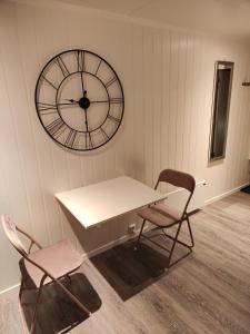 a table and two chairs and a clock on a wall at Apartament 1 Havoysund in Havøysund