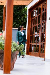 een vrouw in een groen pak die voor een deur staat bij Greenside Hotel in Arusha