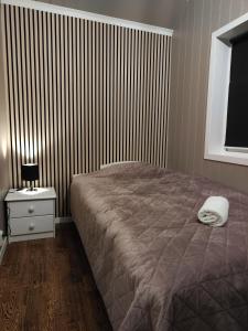 a bedroom with a bed and a nightstand and a window at Apartament 2 in Havøysund