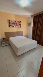 1 dormitorio con 1 cama blanca grande en una habitación en Apartamentos Boulevard, en Caldas Novas