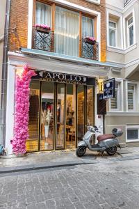 イスタンブールにあるAPOLLO HOTEL & APARTMENtSのピンクの花が咲く店前に停まったスクーター