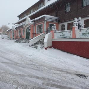 un edificio con nieve en el suelo delante de él en Hotel Tauplitzerhof en Tauplitz
