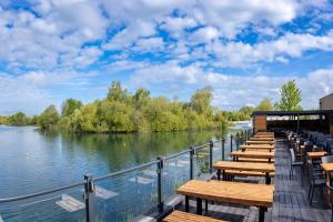 a row of tables and chairs next to a river at Lodge at Chichester Lakeside 2 Bed in Chichester