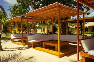 فندق Arraial Bangalô Praia في ارايال دايودا: جناح خشبي مع كنب وطاولات على شاطئ