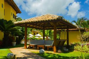 فندق Arraial Bangalô Praia في ارايال دايودا: شرفة خشبية مع مقعد في الفناء