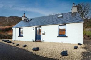 a white house with rocks in front of it at 176 Marrell in Helmsdale