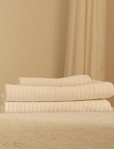 three white towels stacked on top of a bed at La Arena studio in Puerto de Santiago