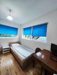 1 dormitorio con 1 cama, escritorio y 2 ventanas en Casa Thomas Cluj en Cluj-Napoca