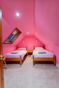 a room with two beds in a pink room at 176 Marrell in Helmsdale