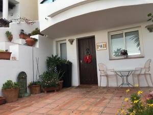Palm Beach Apartment in La Duquesa في مانيلفا: باب أمام منزل به نباتات الفخار