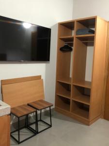 a room with a bench and a tv and a shelf at Flat em Juquehy in São Sebastião