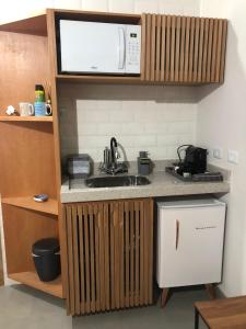 a kitchen with a sink and a microwave at Flat em Juquehy in São Sebastião