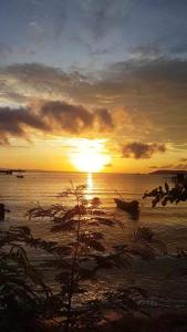 una puesta de sol en la playa con barcos en el agua en The Hut Koh Mak Sea View, en Ko Mak