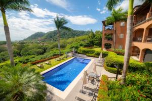 una vista exterior de una casa con piscina y palmeras en Los Suenos Resort Alta Vista 5A, en Herradura