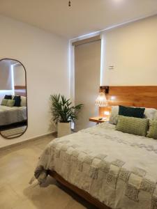 a bedroom with a large bed and a mirror at Las Huayitas, by Casa Amaranto in Mérida