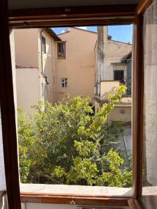 a window with a view of a tree and buildings at Spacious apartment near Arno river in Florence