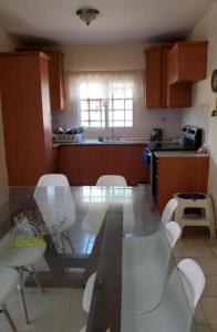 uma cozinha com uma mesa de vidro e cadeiras brancas em Casa en la playa puerto cortes em Puerto Cortes