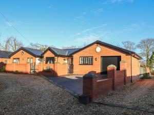 a brick house with a fence and a driveway at Damson Cottage in Poulton le Fylde