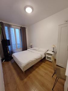 - une chambre blanche avec un lit et une chaise dans l'établissement Josef appartment, à Paris