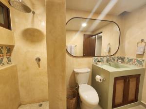 y baño con aseo, lavabo y espejo. en Las Huayitas, by Casa Amaranto, en Mérida