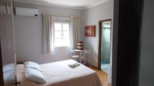 um quarto com uma cama, uma janela e um espelho em Victoria Hotel - Campanha - MG em Campanha