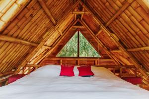 two red pillows sitting on a bed in a wooden cabin at Designers Luxury Retreat with breathtaking gardens in Tzununá