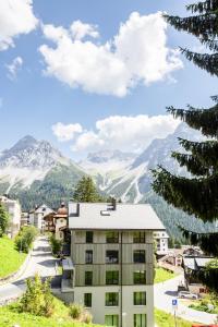 a building on a hill with mountains in the background at Haus Burgermeister Wohnung Schiesshorn in Arosa