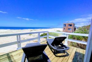 un balcón con 2 sillas y la playa en Las Rochas, Suites de Mar, en Punta del Diablo