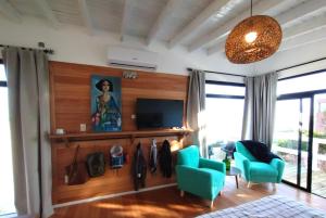 sala de estar con sillas azules y TV en Las Rochas, Suites de Mar, en Punta del Diablo