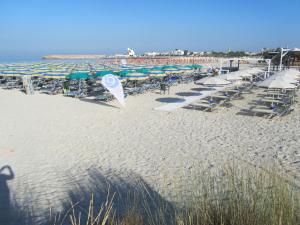 einen Sandstrand mit Liegestühlen und Sonnenschirmen und dem Meer in der Unterkunft Vivere nel Salento in Torre San Giovanni Ugento