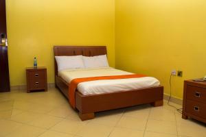 1 dormitorio con cama y pared amarilla en Kipepeo Sky View en Nairobi