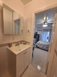 a bathroom with a sink and a mirror and a bedroom at Brand new studio apartment in Vero Beach