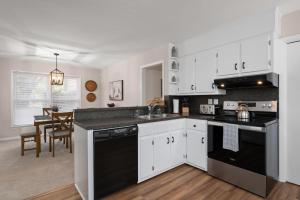 una cocina con armarios blancos y electrodomésticos negros en Salisbury Cottage en Salisbury