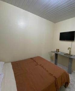a bedroom with a bed and a desk and a television at Aconchego de Maria in Piranhas