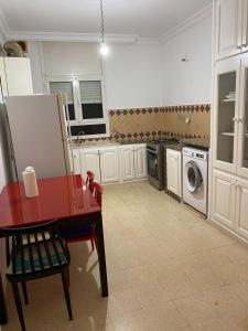 a kitchen with a red table and a washing machine at BENSASSI Urban Escape Premium in La Marsa