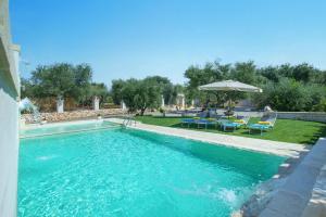 - une grande piscine avec des chaises et un parasol dans l'établissement Villa Amico by Villa Plus, à Grottaglie