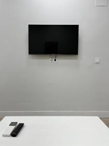 uma televisão numa parede branca com dois comandos à distância em Exyca Tetuán em Madri